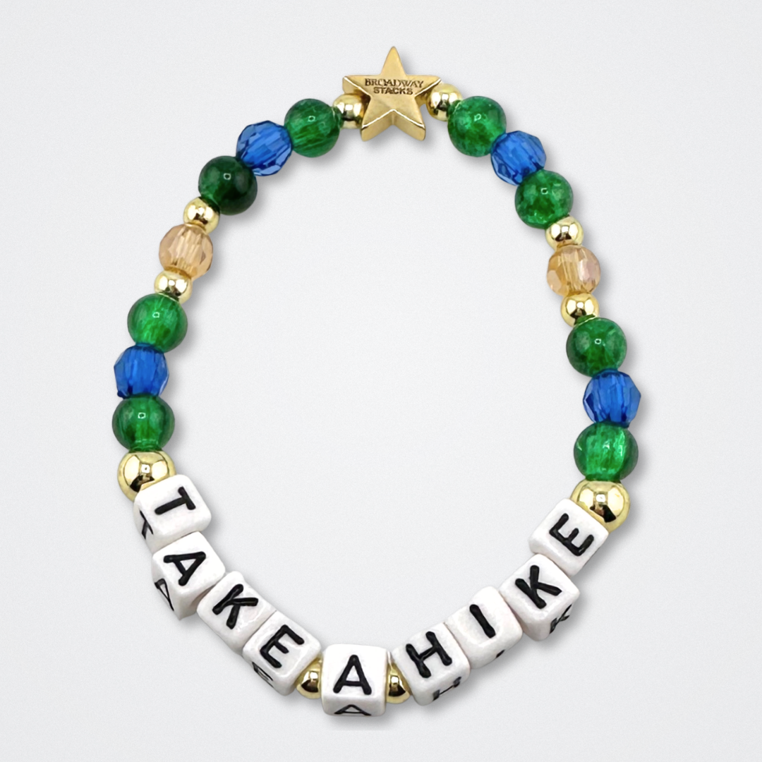 Broadway Stacks TAKE A HIKE bead bracelet. Green, blue, tan and gold color beads on a gray background.