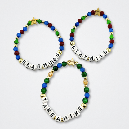 Broadway Stacks MOUNTAIN Collection bead bracelets. Green, blue, dark red and gold color jewelry displayed flat on a gray background.