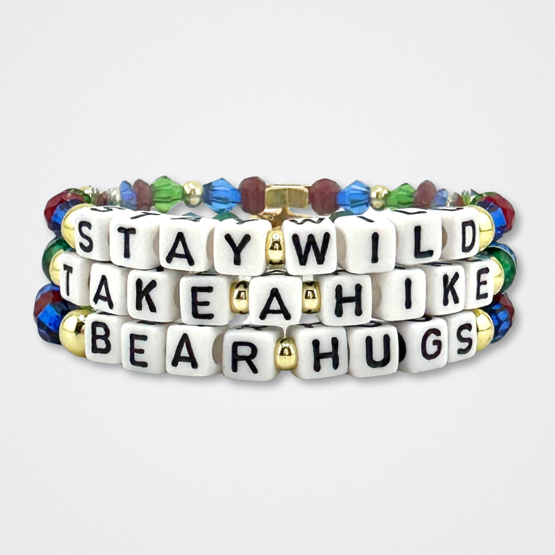 Broadway Stacks MOUNTAIN Collection bead bracelets. Green, blue, dark red and gold color jewelry stacked on a gray background.