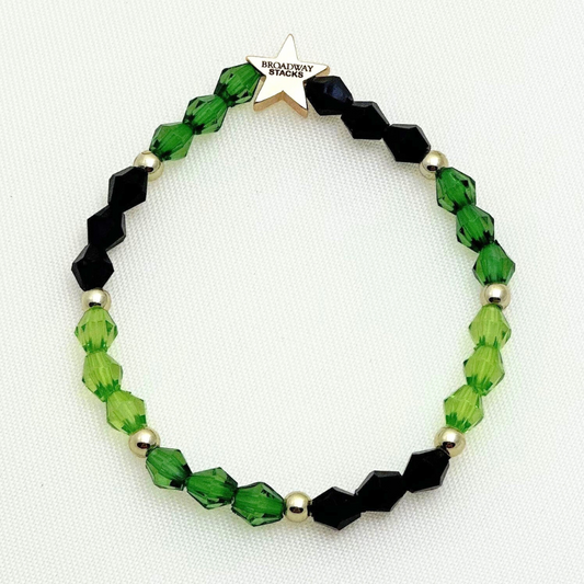 Broadway Stacks Witch collection. 3 stretch bracelets included in Stack. Greens, pinks, black and gold colored beads. Letter beads that spell Wicked. Gold star logo bead on every bracelet. 