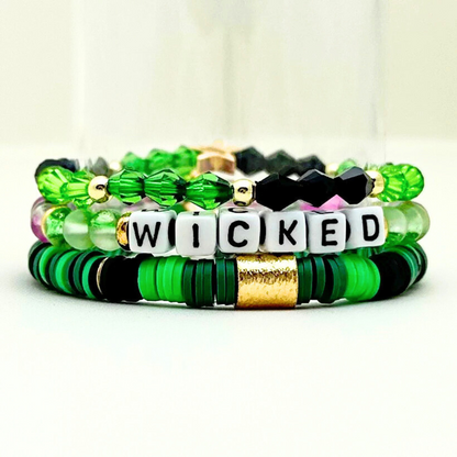 Broadway Stacks Witch collection. 3 stretch bracelets included in Stack. Greens, pinks, black and gold colored beads. Letter beads that spell Wicked. Gold star logo bead on every bracelet. 