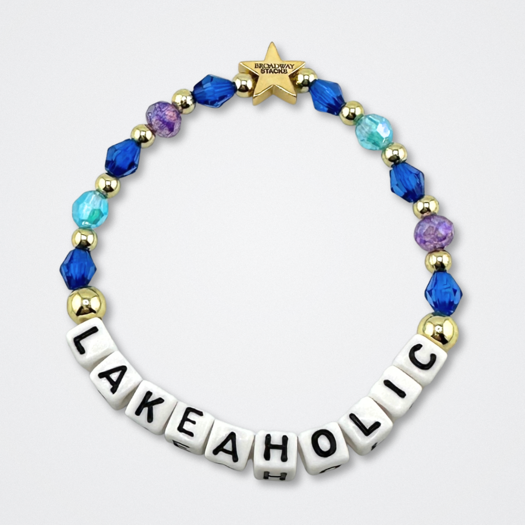 Broadway Stacks LAKEAHOLIC bead bracelet. Blues, purple and gold color beads on a gray background.