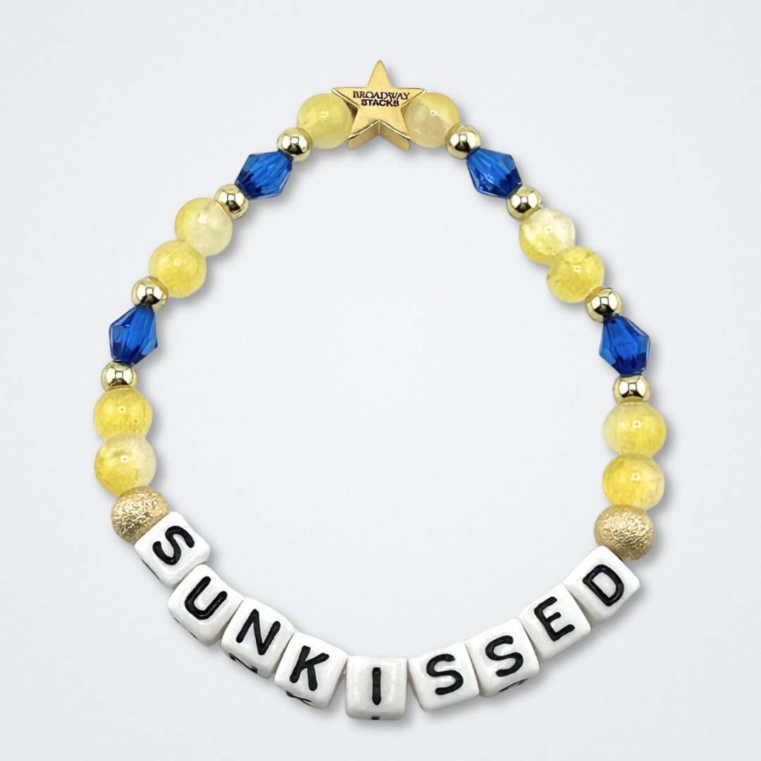 Broadway Stacks SUNKISSED bead bracelet. Yellow, blue and gold color beads on a gray background.