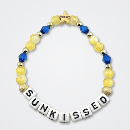 Broadway Stacks SUNKISSED bead bracelet. Yellow, blue and gold color beads on a gray background.